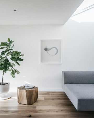 A contemporary living area featuring a gray sofa a unique wooden table and a large leafy plant. Natural light pours in enhancing the ambiance and minimalist decor.の素材