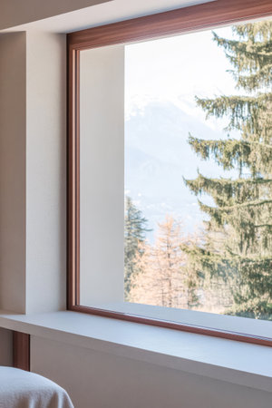 A spacious window reveals a stunning mountain landscape with towering trees. Sunlight floods a warm interior creating a peaceful atmosphere ideal for relaxation.の素材