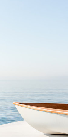 A small wooden boat rests on a serene shoreline under a clear sky at sunrise. The calm water reflects the soft colors of dawn creating a peaceful atmosphere for a relaxing morning.の素材