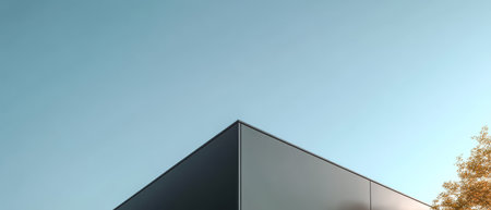 A sleek geometric structure features a sharp roofline and minimalistic design. Framing the scene are vibrant autumn leaves highlighting the contrast with the clear blue sky.の素材