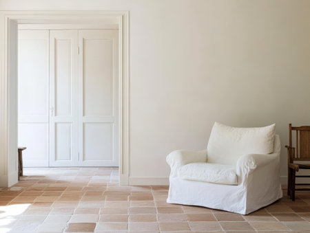 A bright spacious room showcases a white armchair and a wooden chair on a tiled floor. The contemporary space emphasizes simplicity and natural light with uncluttered walls.の素材