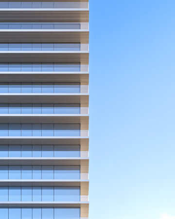 A sleek modern high-rise building stands prominently against a clear blue sky. The structure features several balconies and large glass windows showcasing contemporary architecture.の素材