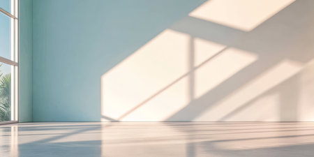 Sunlight pours into an empty room featuring a light blue wall and modern flooring. Long shadows create interesting patterns across the space enhancing the tranquil atmosphere.の素材