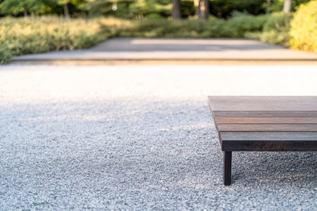 A wooden bench sits empty in a tranquil outdoor setting filled with greenery. Gravel paths lead through the garden creating a peaceful atmosphere for relaxation.の素材