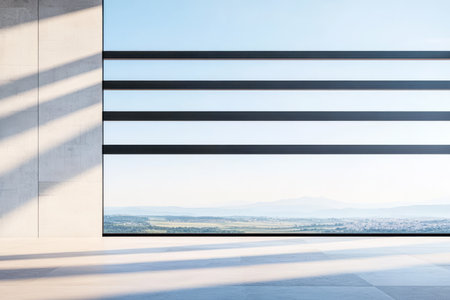 Light streams through large horizontal windows illuminating a sleek interior space. Outside a vast landscape stretches into the distance under a clear blue sky.の素材