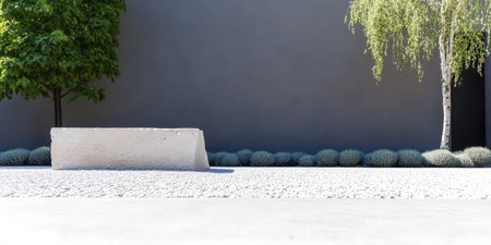 A minimalist concrete bench sits in a serene outdoor area surrounded by neatly trimmed greenery. The scene is illuminated by direct sunlight highlighting the design and textures.の素材