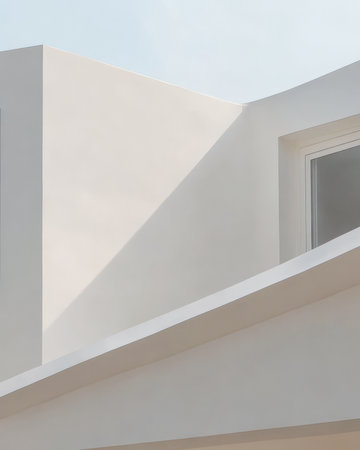 A contemporary building showcases minimalistic architecture with smooth surfaces and sharp angles. The sunlight casts gentle shadows highlighting the structures clean forms and innovative design.の素材