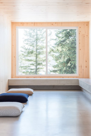 Soft cushions are arranged in a calm meditation area featuring a large window that offers a serene view of trees. Natural light brightens the wooden interior creating a peaceful atmosphere.の素材