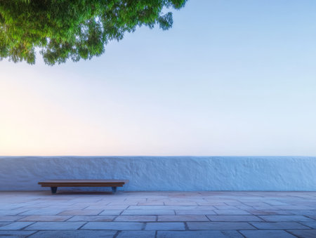 A wooden bench sits quietly beneath a lush green tree facing a vast peaceful expanse in the twilight. The soft glow of dusk highlights the calm atmosphere.の素材