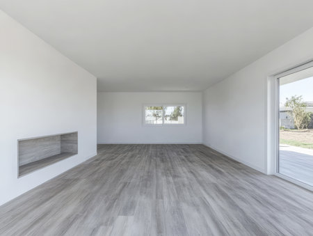 Spacious room features white walls and a light wooden floor illuminated by natural light pouring through large windows. A simple fireplace niche adds an accent to the minimalist style.の素材
