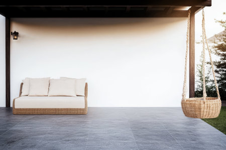 A stylish outdoor space features a comfortable wicker sofa and a hanging swing chair perfect for relaxation. The minimalist design and calm colors create a serene atmosphere.の素材