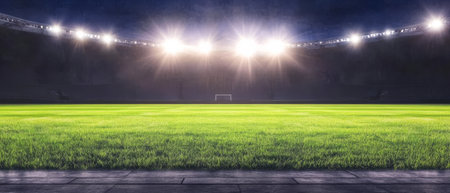 The football field is illuminated with bright stadium lights showcasing lush green grass and a well-maintained pitch setting the stage for an exciting evening of competition.の素材