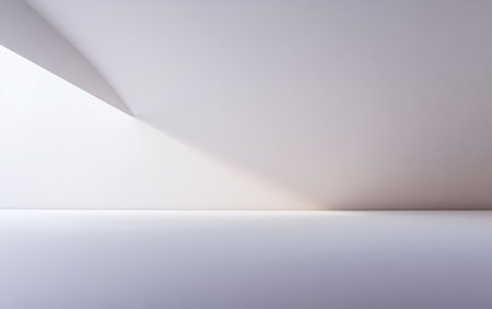 Soft light creates delicate shadows in a simple minimalist interior space with white walls and flooring. The geometric lines draw attention to the tranquility and elegance of the environment.の素材