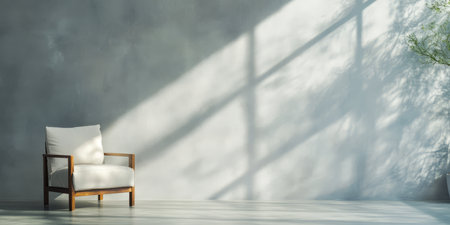 A single modern armchair sits against a textured gray wall where gentle morning light filters through. Soft shadows cast intricate patterns on the floor enhancing the serene atmosphere.の素材