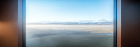 A stunning view captures a misty landscape featuring distant mountains under a clear blue sky. The scene is tranquil and bathed in soft morning light evoking a sense of calmness.の素材