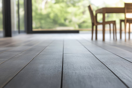 A close-up view of a dark wooden floor captures sunlight streaming into a modern dining area. The tranquil surroundings enhance the simplicity of the space creating a warm ambiance.の素材