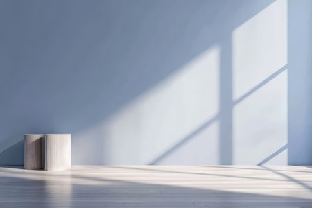 Soft sunlight streams through large windows casting gentle shadows on a light blue wall. A simple wooden block sits on the elegant floor creating a serene atmosphere.の素材