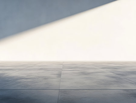 Sunlight streams through an unseen window creating a stark contrast on an empty polished concrete floor. The simplicity and light enhance the minimalist aesthetic of the interior.の素材
