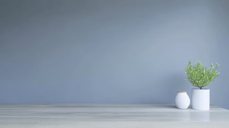 A serene indoor setting features a wooden table with a white vase and a potted green plant against a soft gray wall. The arrangement emphasizes simplicity and tranquility.の素材