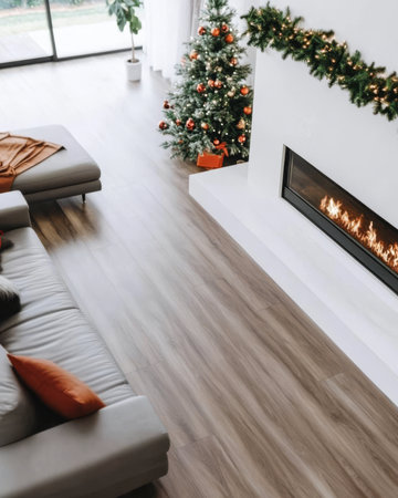 A warm living room features a beautifully decorated Christmas tree and a glowing fireplace. Soft furnishings and a festive atmosphere invite relaxation and celebration.の素材