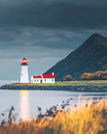 A striking lighthouse with a red roof sits near a mountain reflecting on calm waters during twilight. Surrounding landscapes display vibrant autumn colors enhancing the tranquil atmosphere.の素材