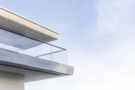 A contemporary balcony showcases an elegant design with glass railings set against a backdrop of soft clouds. The structure highlights minimalism and modern aesthetics creating a serene atmosphere.の素材
