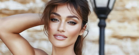 A woman displays her beauty with subtle makeup and a confident expression standing near a street lamp in a charming outdoor environment.の素材