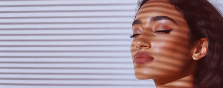 A model is relaxing and posing with her eyes closed her face softly illuminated by light creating interesting shadows. The modern indoor setting adds to the calm atmosphere.の素材
