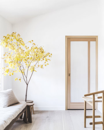 A beautifully designed room features a yellow-leaved tree a wooden door and light-colored furnishings. Soft natural light illuminates the tranquil space creating a serene atmosphere.の素材