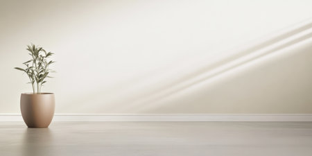 A simple indoor setting showcases a potted plant beside a wall. Soft natural light casts shadows creating a tranquil atmosphere in this minimalistic environment.の素材