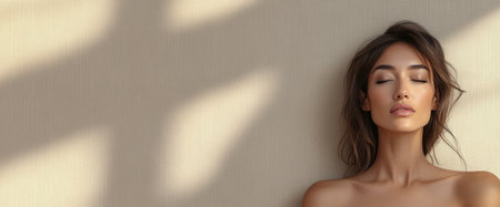 A young model is seen with closed eyes exuding calmness. She stands against a textured wall. Soft natural light casts gentle shadows creating a serene atmosphere.の素材