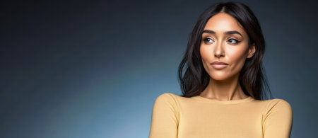 A woman with long dark hair stands with her arms crossed. She has a thoughtful expression showcasing her elegant features. The background features a smooth gradient in blue and gray tones.の素材