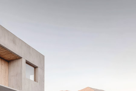 A contemporary structure blends seamlessly with the landscape during dusk. The building features a mix of concrete and wood surrounded by soft natural tones and the distant mountains.の素材