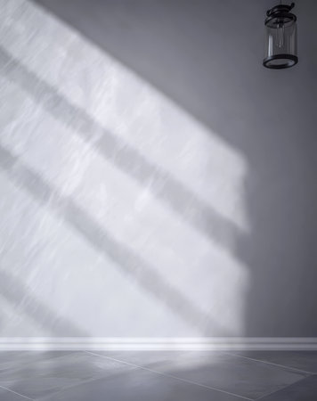 Natural light creates soft shadows on a smooth gray wall enhancing the clean lines of a minimalist interior. A hanging lantern casts a warm glow adding charm to the serene atmosphere.の素材