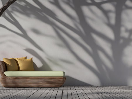 A peaceful outdoor seating area features a comfortable couch adorned with yellow cushions. The intricate shadows of a tree stretch across the light wall creating a tranquil atmosphere.の素材