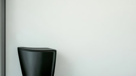 A sleek black chair stands against a plain white wall showcasing minimalist design. The simplicity of the furniture enhances the modern ambiance of the area emphasizing clean lines.の素材
