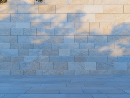 A smooth light-colored stone wall displays subtle shadows cast by nearby trees. The scene is illuminated by warm golden hour light creating an inviting urban atmosphere.の素材