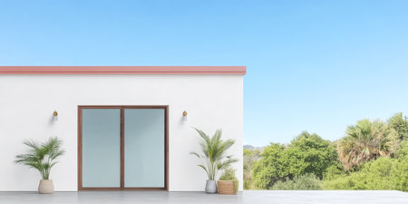 A minimalist house features large glass windows and a clean white facade. Lush greenery surrounds the property under a clear blue sky creating a serene environment.の素材