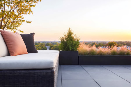 Soft cushions enhance the comfort of a stylish outdoor sofa positioned on a rooftop terrace overlooking a serene landscape bathed in the warm hues of sunset.の素材
