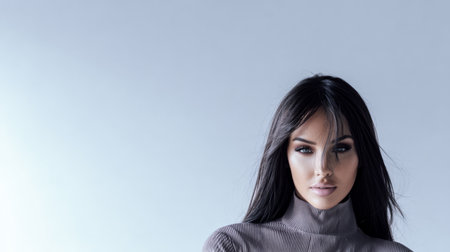 A female model stands with a poised expression wearing a chic sweater. The clean light backdrop emphasizes her features and outfit creating a striking visual impression.の素材