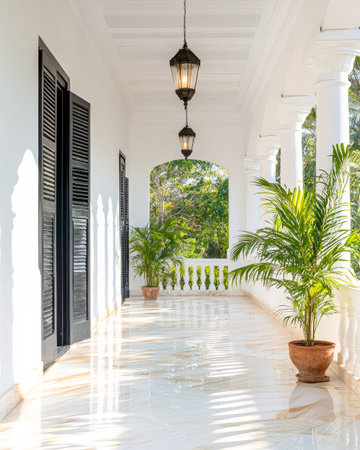 Sunlight floods a charming corridor adorned with lush greenery and vintage lanterns. The polished marble floor reflects light, enhancing the tranquil atmosphere of this tropical escape.の素材