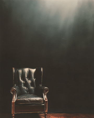 A classic black leather armchair sits alone in a dimly lit room. Soft light highlights its textured upholstery, casting shadows and enhancing its elegant design.の素材