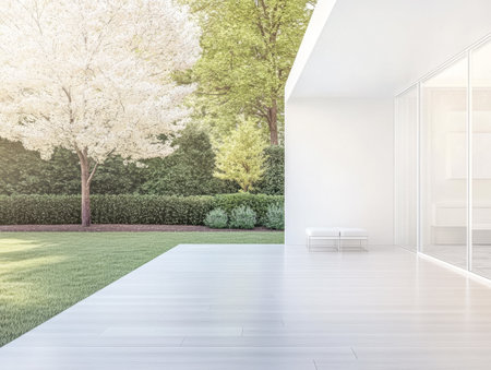 Expansive patio area features sleek flooring and a minimalist bench surrounded by vibrant greenery and a blooming tree, perfect for outdoor relaxation during sunny days.の素材