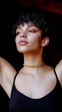 A young woman with short curly hair strikes a confident pose while wearing a black top and a gold necklace. The warm lighting enhances her features and creates an elegant ambiance.の素材