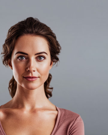 A young woman stands confidently, gazing directly at the viewer with a calm expression. She has wavy hair and a soft complexion, creating a warm and inviting presence.の素材