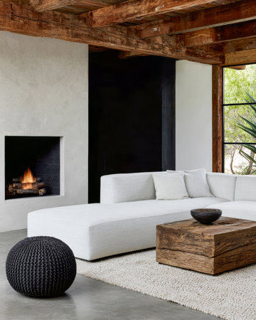 This living room features a sleek white sectional sofa, a rustic wooden coffee table, and a smooth fireplace. Natural light fills the area, creating a welcoming atmosphere.の素材