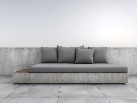 A sleek gray sofa with multiple cushions is placed against a simple concrete wall. The room has a bright, open feel, enhanced by natural light streaming in.の素材