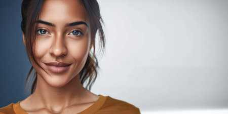 A woman is smiling warmly, wearing an orange shirt. Soft morning light illuminates her face in a bright indoor space, highlighting her natural beauty and happiness.の素材