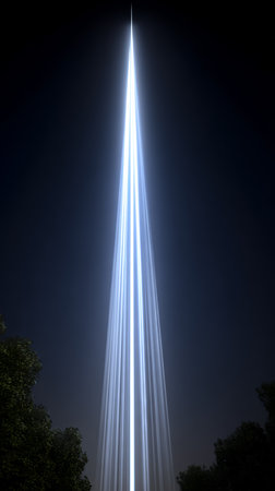 A strong vertical beam of light pierces the night sky, illuminating the darkness. This striking display creates a mesmerizing contrast against the backdrop of trees and clear weather.の素材