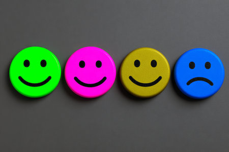 Four round smiley face icons in bright colors represent various emotions. These icons include green, pink, gold, and blue, showcasing happiness and sadness.の素材